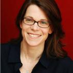Photo of professor Susan Schulten. This image is a head shot, showing Susan in front of a red plain background. She is has long reddish-brown hair that is parted on her right side, and she wears rectangle-shaped eyeglasses. She is pictured here wearing a black button-up shirt and a silver pendant.
