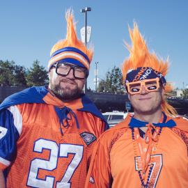 2 Broncos Superfans wearing orange jerseys and orange wigs.