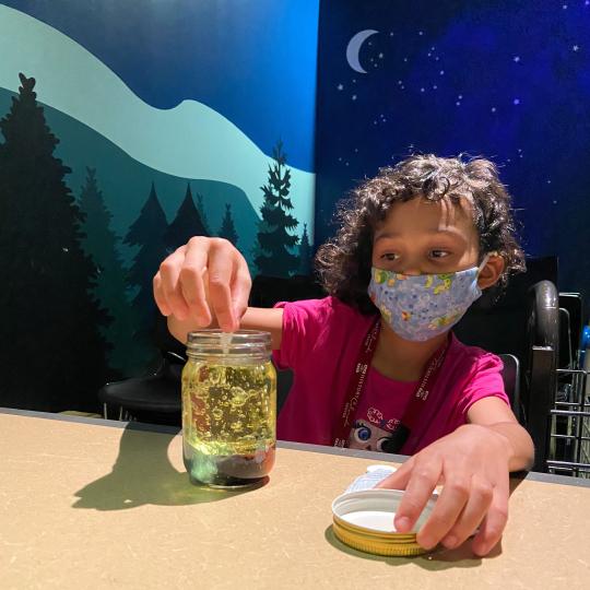 Masked Hands-On History child participant doing an experiment with a jar.